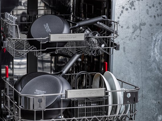 Twee zwarte KitchenAid koekenpannen boven elkaar in een vaatwasser.