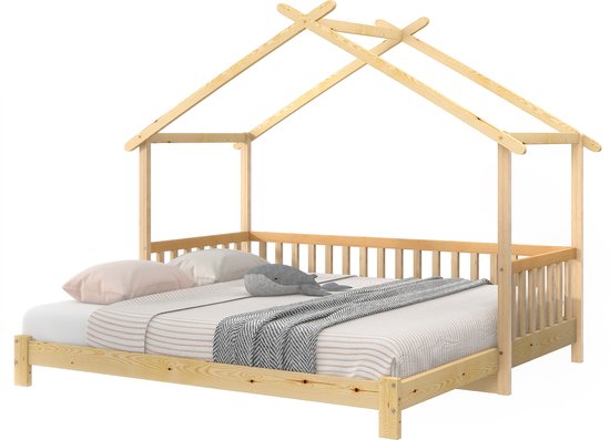 Houten huisbed met spijlen en een deken, met kussens en een knuffel op de matras.