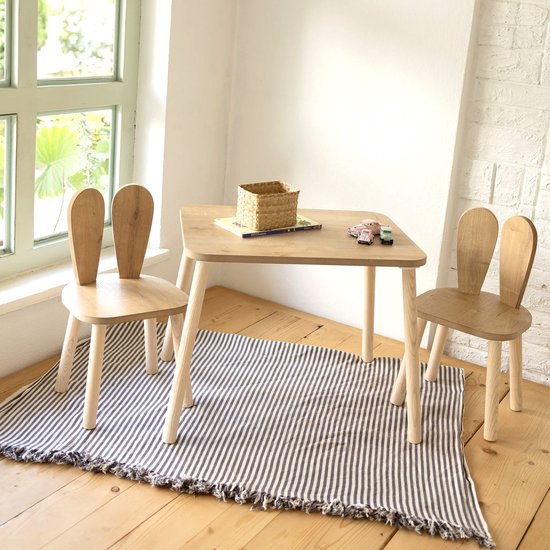 Houten kindertafel met twee stoeltjes met konijnenoren, op een gestreept vloerkleed.