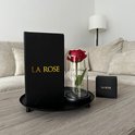 Een rode roos in glazen stolp, met een grote en kleine 'LA ROSE' geschenkdoos op een dienblad.