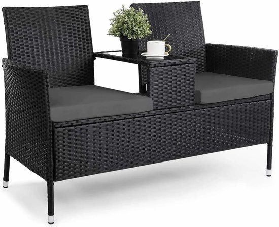 Zwarte rotan tweezitsbank met grijze kussens en een geïntegreerde bijzettafel met plant.
