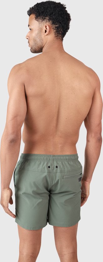 Homme en short de bain vert vintage, regardant par-dessus son épaule. Cordon de serrage noir visible.