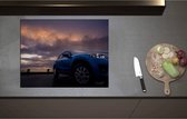 Inductieplaat Beschermer - Blauwe Auto in Regenbui onder Donkere Bewolking - 71x55 cm - 2 mm Dik - Inductie Beschermer - Bescherming Inductiekookplaat - Kookplaat Beschermer van Zwart Vinyl