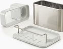Zilverkleurige gootsteen organizer, beige onderzetter en witte scheidingswand met handvatten.