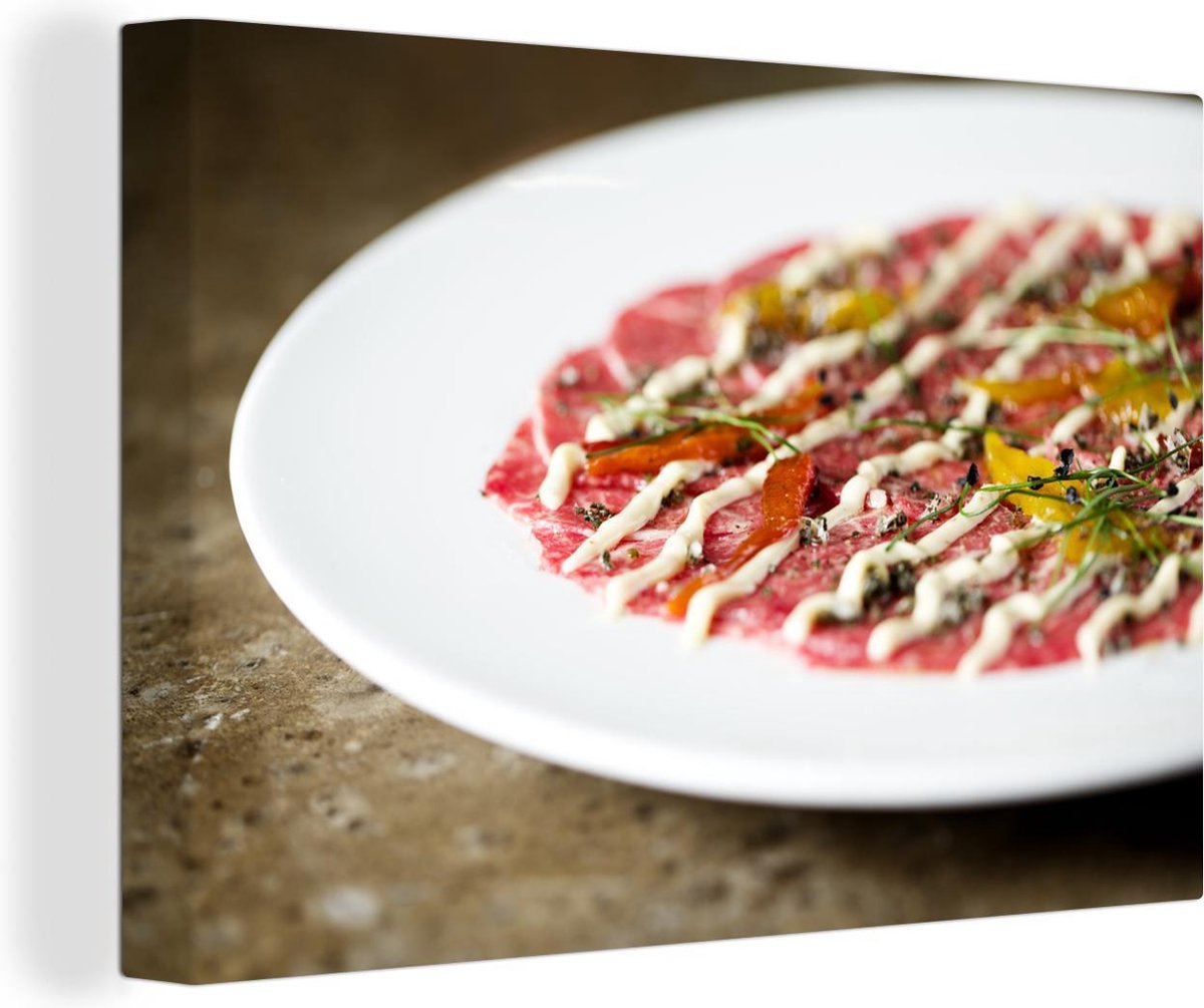 Canvas Schilderij Rundercarpaccio gegarneerd met een tomatensalade en kruiden 120x80...