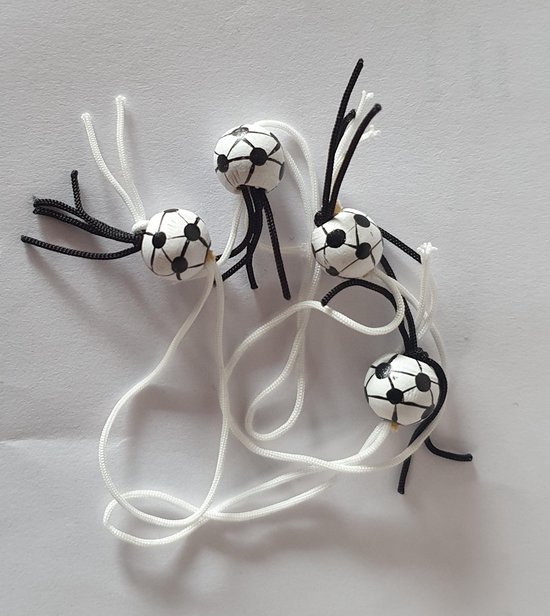 Vier kleine gelukspoppetjes met een voetbalprint, versierd met zwarte en witte koordjes.