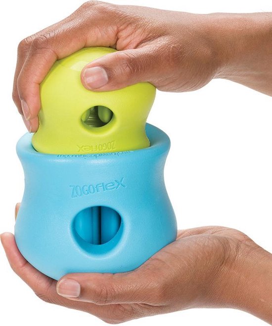 Handen vullen een blauw speeltje met een groen speeltje.
