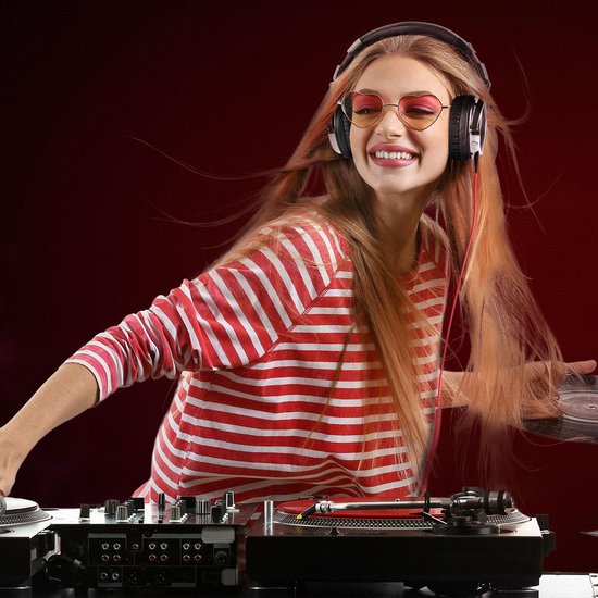 Vrouw met blonde haren en zonnebril, draagt een rood-wit gestreepte trui en zwarte Studio DJ koptelefoon bij een DJ-set.