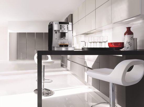 Zilverkleurige De'Longhi Magnifica S volautomatische espressomachine in een moderne keuken met witte bar.