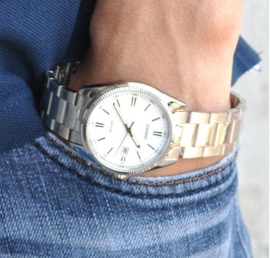Montre Casio argentée à cadran blanc portée au poignet d'un homme.