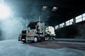 Grijze LEGO Technic Mack Anthem truck met witte container en groene kraan, op een donkere ondergrond met rook.