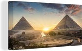 Canvas Schilderij Zonsondergang tussen de piramides van de Egyptische stad Caïro - 40x20 cm - Wanddecoratie