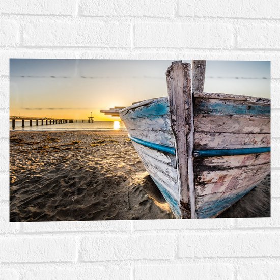 WallClassics - Muursticker - Zonsondergang achter Gestrande Blauw met Witte Houten Boot - 60x40 cm Foto op Muursticker
