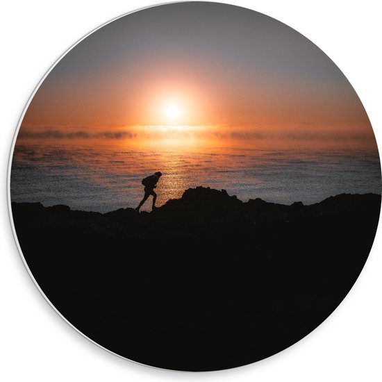 WallClassics - PVC Schuimplaat Muurcirkel - Man lopend over Berg aan de Zee met Zonsondergang - 30x30 cm Foto op Muurcirkel (met ophangsysteem)