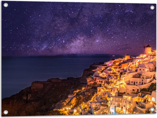 Tuinposter – Verlicht Dorp in de Nacht aan het water met de Melkweg in de Lucht - 80x60 cm Foto op Tuinposter (wanddecoratie voor buiten en binnen)