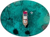 WallClassics - Dibond Ovaal - Bovenaanzicht van Schip op Felblauwe Oceaan met Rotsen - 56x42 cm Foto op Ovaal (Met Ophangsysteem)
