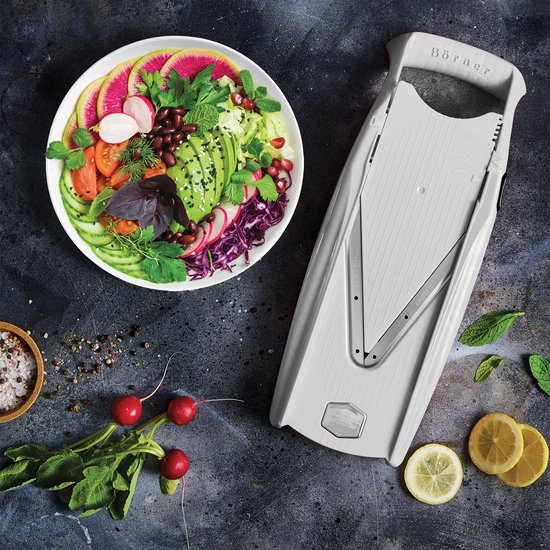 Witte Börner V5 mandoline naast een schaal met een kleurrijke salade van avocado, tomaat, komkommer, rode kool en radijsjes.