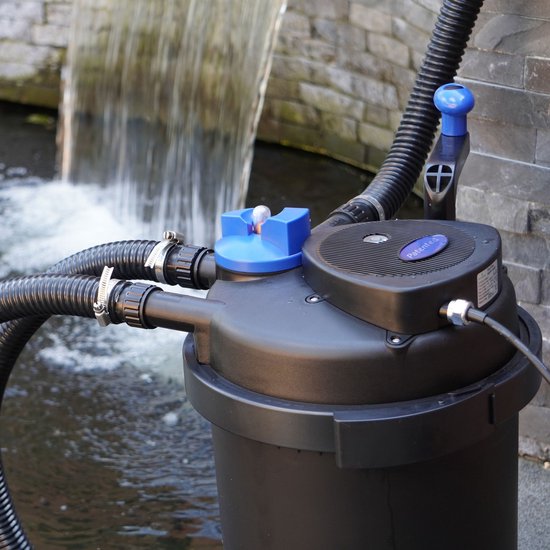 Zwarte vijverfilter met blauwe dop en handgreep, naast een waterval.