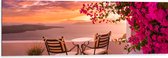 Dibond - Tafel met Stoeljes op Balkon met Roze Bloemenstruik met Uitzicht op Zee - 120x40 cm Foto op Aluminium (Wanddecoratie van metaal)