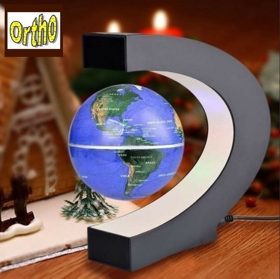 Globe terrestre flottant avec continents verts et océans bleus, sur un support noir en forme de C avec éclairage LED, avec une maison en pain d'épices en arrière-plan.