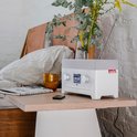 Witte Teufel radio met grijs rooster op een houten nachtkastje, met bloemen en een glas.