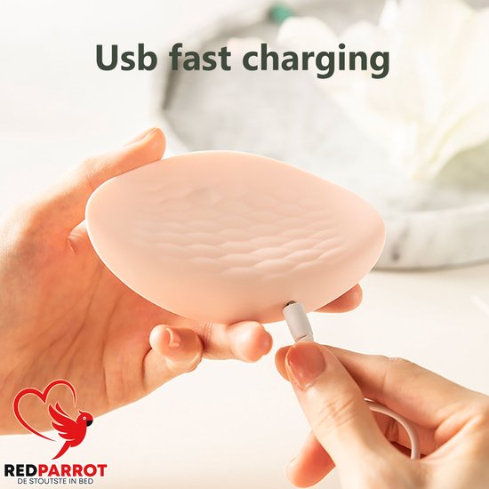 Roze tepelstimulator met honingraattextuur en USB-kabel die wordt aangesloten.