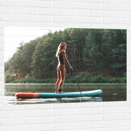 Muursticker - Blonde Vrouw op Supbord op Water langs Rij Bomen - 120x80 cm Foto op Muursticker