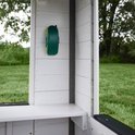 Detail van de buitenkant van het witte speelhuis: groene telefoonhouder aan de muur.