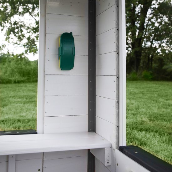 Detail van de buitenkant van het witte speelhuis: groene telefoonhouder aan de muur.