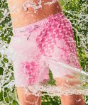 Jongen met zwembroek met roze grafisch patroon, met waterstralen.