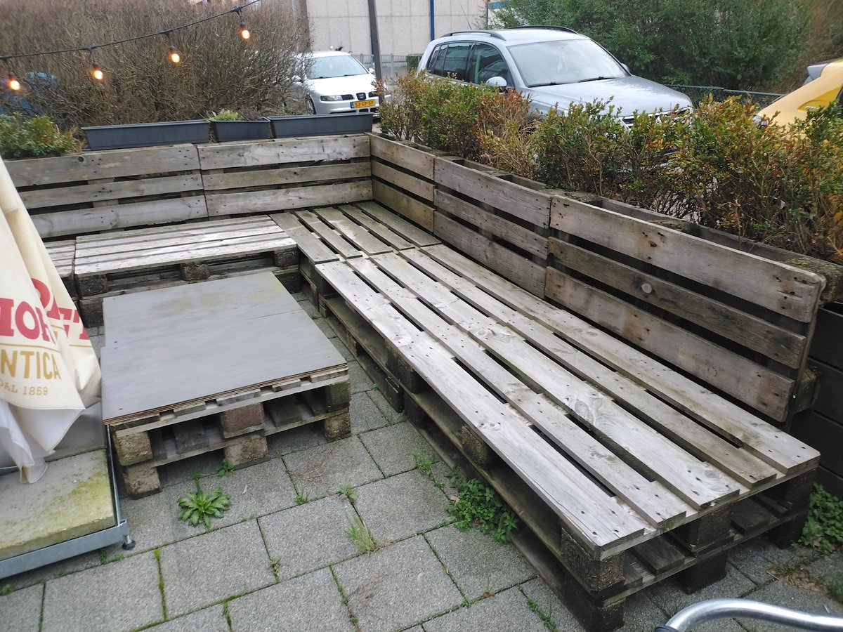 Stijlvolle Palletbank Loungeset in naturel hout met zwarte kussens en lage tafel.