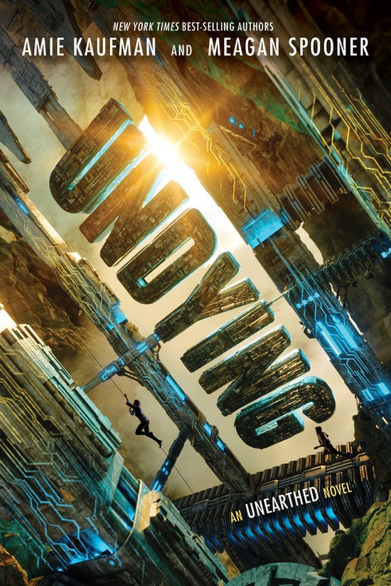 Boekcover voor 'Undying' met de tekst 'New York Times Best-Selling Authors Amie Kaufman and Meagan Spooner'. Goudkleurige letters op een achtergrond van futuristische, metalen constructies met blauwe gloed.