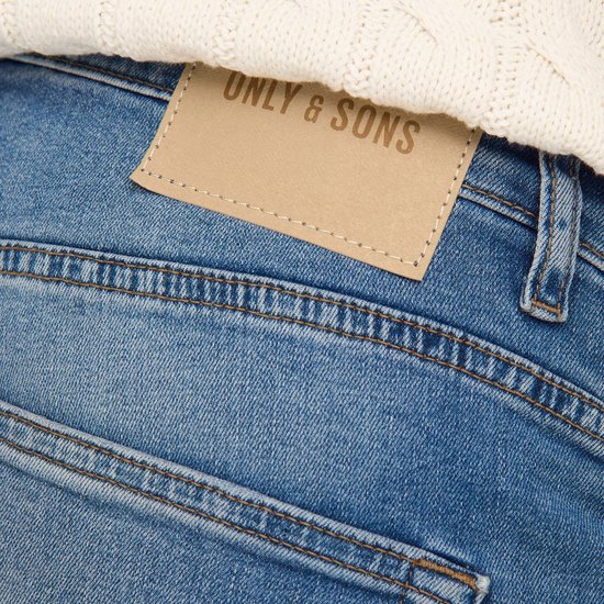 Detail van blauwe jeans met bruin leren logo patch 'ONLY & SONS'.