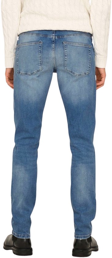 Man met een crème kabeltrui en blauwe jeans, achterkant.