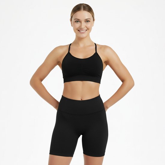 Zwarte sport BH met ruches en korte broek, gedragen door een blonde vrouw met de handen in de zij.