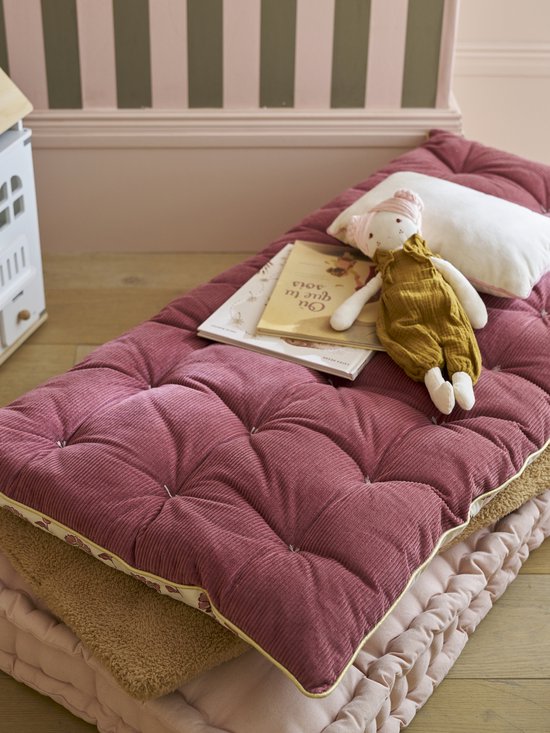 Lichtroze corduroy vloermatras met een goudkleurige bies, met een popje en boek.
