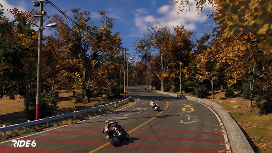 Motorrijders op een weg omringd door herfstbomen.