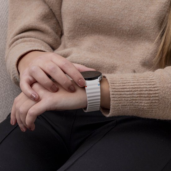 Damespols met een smartwatch en een crèmekleurig siliconen horlogebandje met golvend patroon.