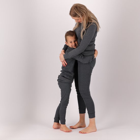 Vrouw en kind omhelzen elkaar, beide gekleed in grijze thermokleding.