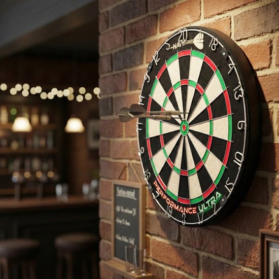 Een dartbord met de traditionele kleuren groen, rood en zwart, met twee pijltjes erin. Hangt aan een bakstenen muur.