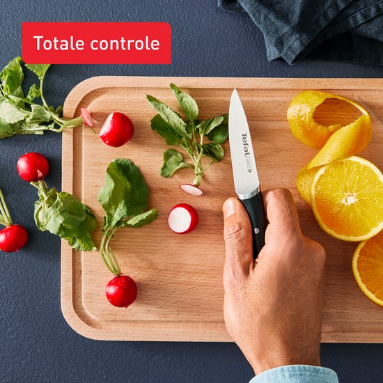 Hand snijdt radijsjes en sinaasappel met Tefal mes op snijplank