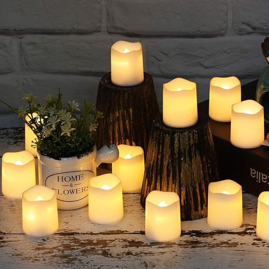 Een groep van ongeveer twaalf witte LED-kaarsen met warme, flikkerende vlammen, gerangschikt rond een witte pot met de tekst 'HOME & FLOWERS'.