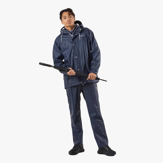 Man in een donkerblauwe regenjas en regenbroek. De jas is glanzend en heeft een capuchon. Hij draagt een paraplu in zijn handen.