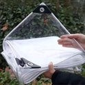 Een transparant zeildoek met versterkte hoeken en oogjes wordt door mensen vastgehouden.
