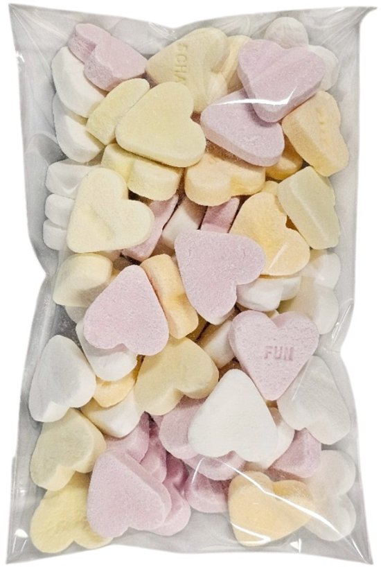 Een zakje vol met hartvormige snoepjes in de kleuren wit, roze en geel. Sommige snoepjes hebben tekst zoals 'FUN'.