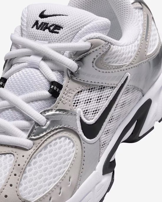 Close-up van de voorkant van een witte Nike sneaker met zilveren details en zwarte swoosh.