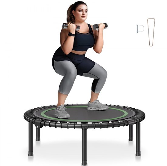 Vrouw met dumbbells, hurkend op een zwarte trampoline met groene rand. Een installatietool is zichtbaar.