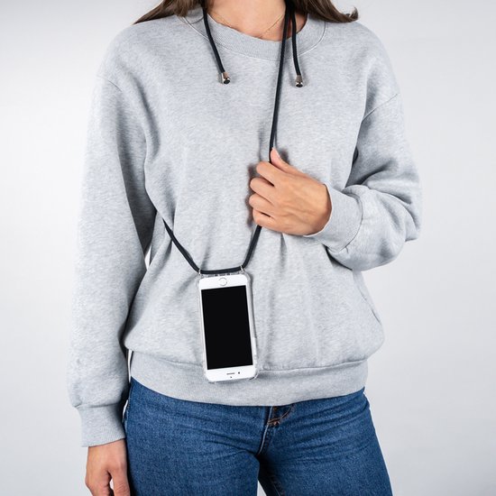 Een vrouw met spijkerbroek en grijze sweater draagt een telefoon met zwarte koord om haar nek.