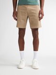 Man van voren gezien in een beige chino short met witte sokken en sneakers.