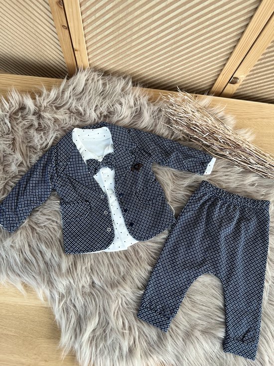 Drie delige baby outfit: donkerblauwe blazer en broek met witte print, wit poloshirt met stippen en strikje.